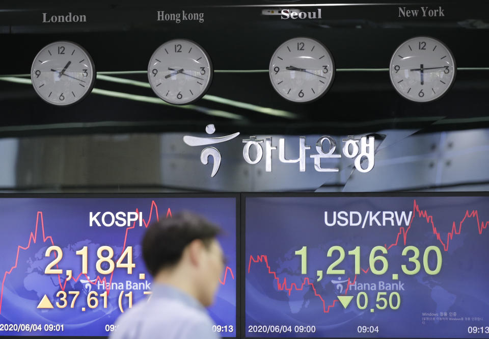 A currency trader walks by the screens showing the Korea Composite Stock Price Index (KOSPI), left, and the foreign exchange rate between U.S. dollar and South Korean won at the foreign exchange dealing room in Seoul, South Korea, Thursday, June 4, 2020. Asian stock markets are mixed after Wall Street rose on better U.S. jobs and manufacturing data than expected.(AP Photo/Lee Jin-man)