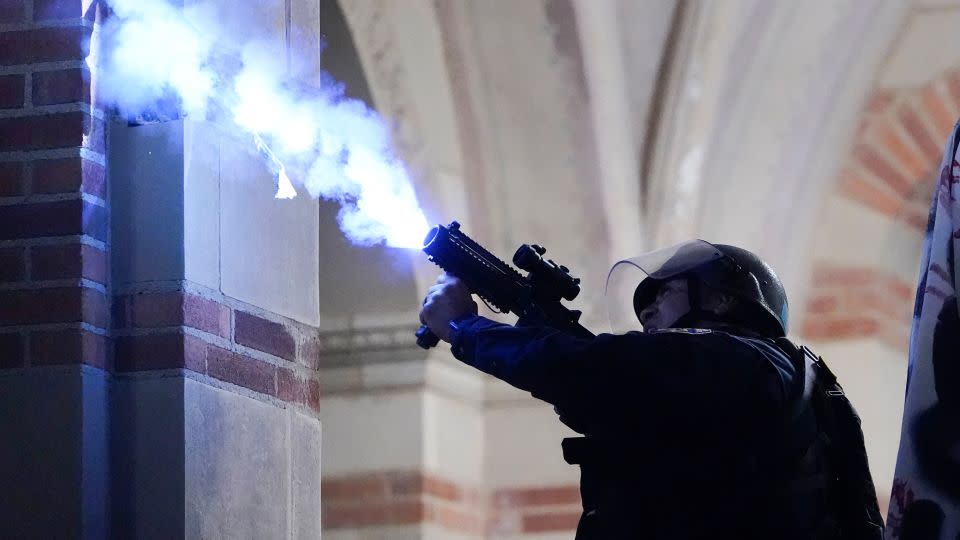 A police officer launches a smoke bomb on the UCLA campus during a raid on a pro-Palestinian encampment on May 2  in Los Angeles. - Ryan Sun/AP