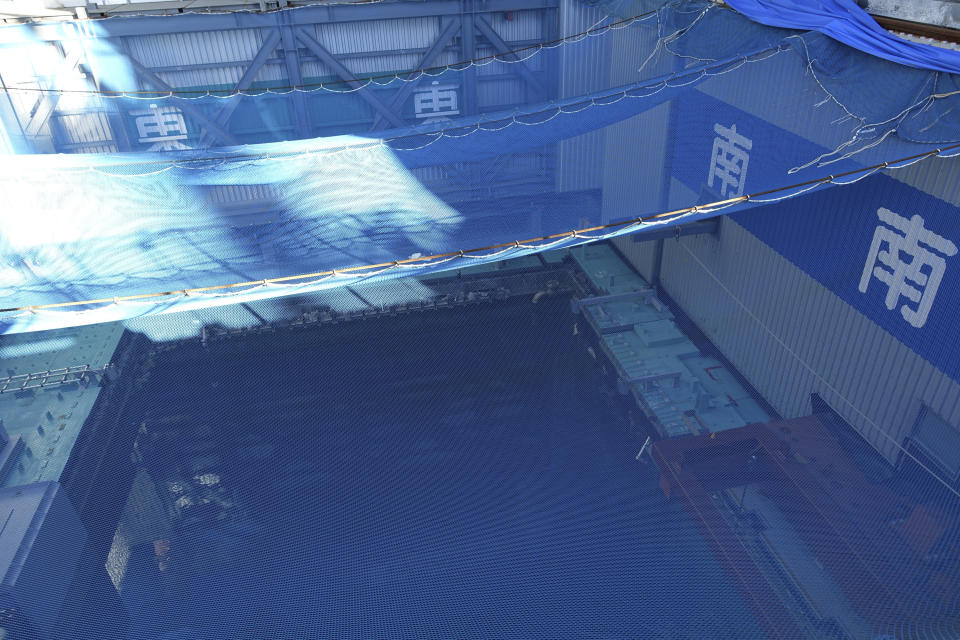 FILE - In this Jan. 25, 2018, file photo, a cooling pool where a total of mostly used 566 sets of fuel rods are stored underwater and covered by a protective net, waits to be removed in a step to empty the pool at Unit 3 of the Fukushima Dai-ichi nuclear power plant ahead of a fuel removal from its storage pool in Okuma, Fukushima Prefecture, northeast Japan. Japan revised a roadmap on Friday, Dec. 27, 2019, for the tsunami-wrecked Fukushima nuclear plant cleanup, further delaying the removal of thousands of spent fuel units that remain in cooling pools since the 2011 disaster. More than 4,700 units of fuel rods remain inside the three melted reactors and two others that survived the 2011 earthquake and tsunami. (AP Photo/Mari Yamaguchi, File)