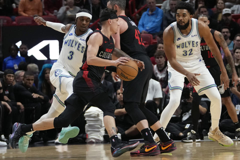 Miami Heat guard Tyler Herro, center, drives to the basket as Minnesota Timberwolves forward Jaden McDaniels (3) and center Karl-Anthony Towns (32) defend during the first half of an NBA basketball game, Monday, Dec. 18, 2023, in Miami. (AP Photo/Lynne Sladky)