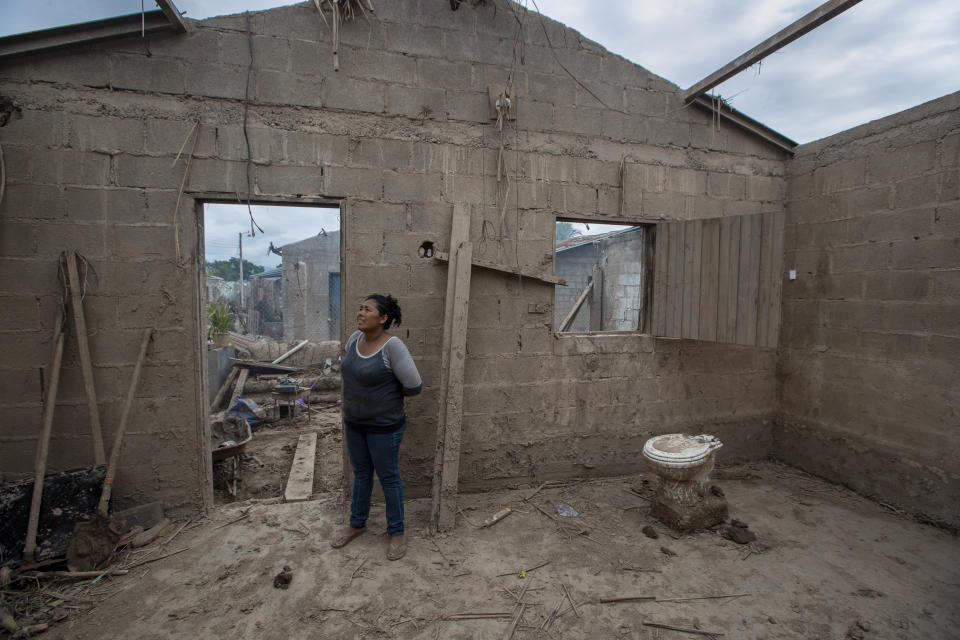 Maria Elena Vasquez stands inside what's left of her home after last year's hurricanes Eta and Iota in La Lima, on the outskirts of San Pedro Sula, Honduras, where she returns every afternoon to remove the mud in hopes of returning to live here, Wednesday, Jan. 13, 2021. Twenty-two years before the 2020 storms, Hurricane Mitch destroyed Vasquez's other home, which was replaced with this one, built by a Catholic charity from Canada. (AP Photo/Moises Castillo)