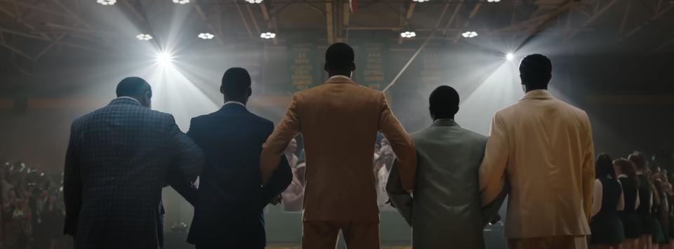 five young men lock arms on a basketball court