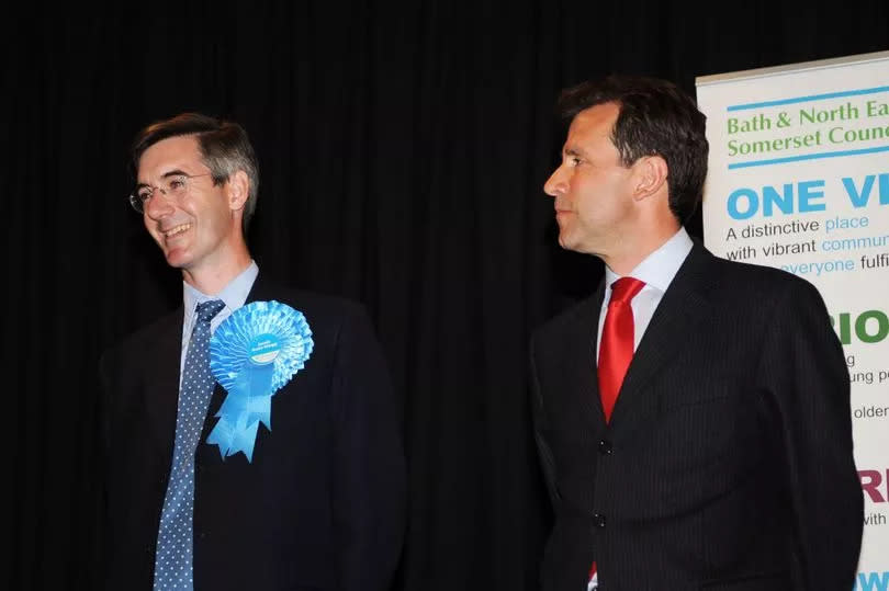 Jacob Rees-Mogg smiles after hearing the results of the North Somerset Constituency, Dan Norris looks on after loosing his seat -Credit:Will Nichol