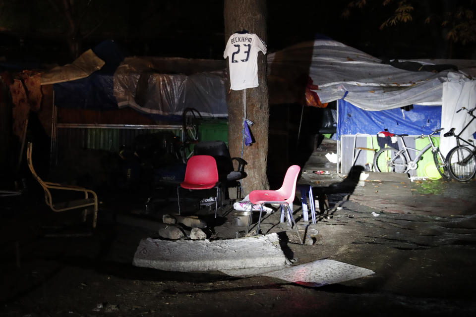 La playera del exfutbolista británico David Beckham cuelga de un árbol durante un operativo para desmantelar un campo de migrantes improvisado en el norte de París, el jueves 7 de noviembre de 2019. (AP Foto/François Mori)