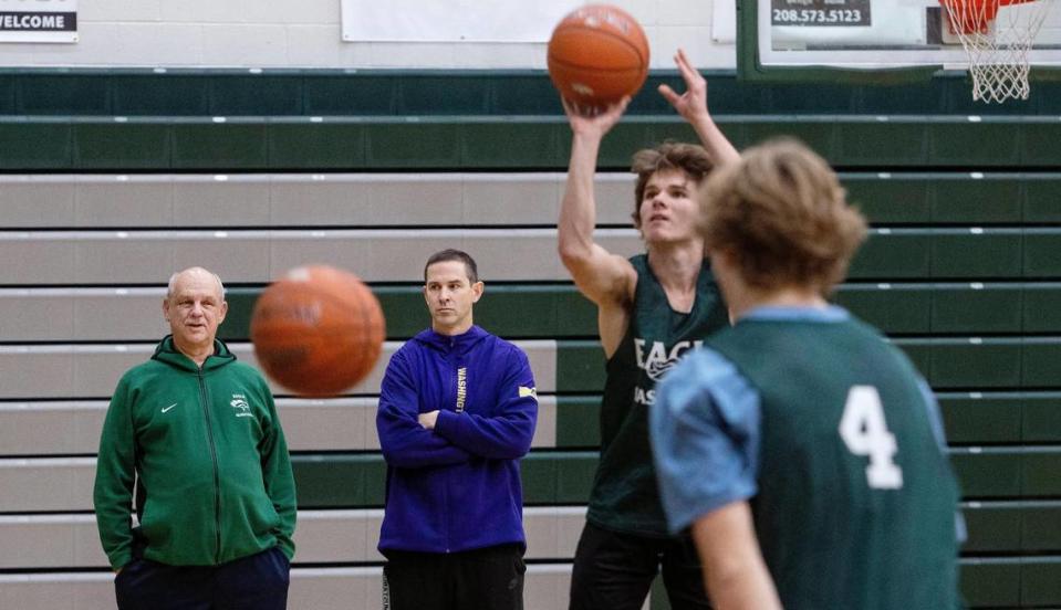 Eagle boys basketball coach Cody Pickett, in purple, watches the Mustangs warm up for practice Friday alongside assistant coach Ron Fortner. Fortner took over the program in Pickett’s absence while he dealt with a 70% blockage in one of his arteries.