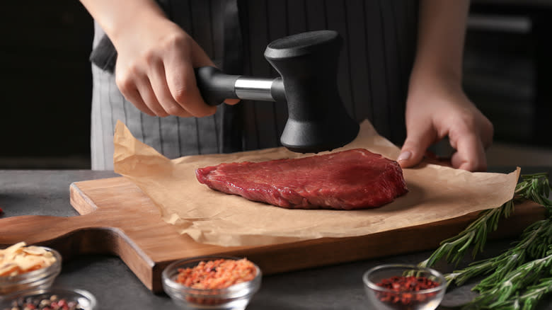 Person tenderizing steak with mallet