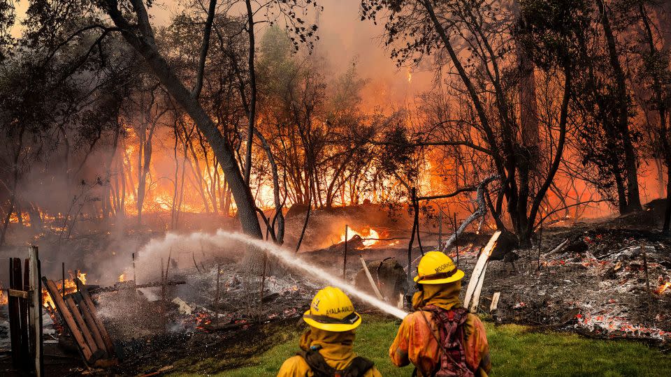 Firefighters spray water while battling the Park Fire in the Cohasset community of Butte County, California, on July 25. - Noah Berger/AP