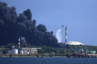 A helicopter dumps water over the Matanzas Supertanker Base, as firefighters try to quell a blaze which began during a thunderstorm the night before, in Matazanas, Cuba, Saturday, Aug. 6, 2022. Cuban authorities say lightning struck a crude oil storage tank at the base, causing a fire that led to four explosions which injured more than 50 people. (AP Photo/Ramon Espinosa)