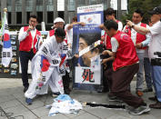 A South Korean protester uses scissors to cut an image of Japanese Prime Minister Shinzo Abe during a rally denouncing the Japanese government's decision on their exports to South Korea in front of the Japanese Embassy in Seoul, South Korea, Tuesday, July 23, 2019. The signs read "Punish economic aggression." (AP Photo/Ahn Young-joon)