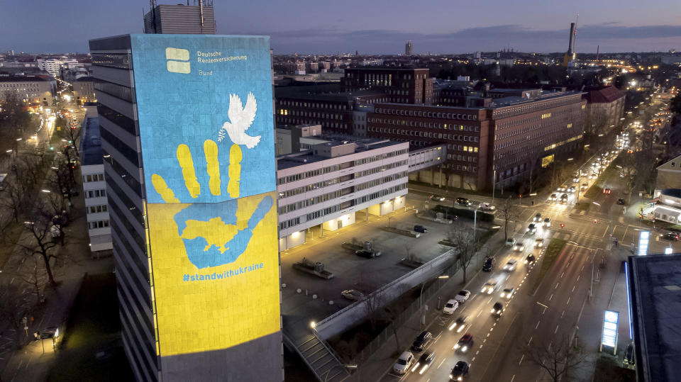 Cars drive past a pro-Ukraine projection on the fifteen floor high building of the 'German Pension Insurance' in Berlin, Germany, Monday, March 7, 2022. (AP Photo/Michael Sohn)