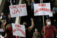FILE - In this Dec. 23, 2020 file photo, demonstrators hold signs that read in Portuguese: "Vaccine now!" and "Get out Bolsonaro," in a protest against Brazilian President Jair Bolsonaro's handling of the new coronavirus pandemic, in Brasilia, Brazil. Despite a half-century of successful vaccination programs, the federal government is trailing regional and global peers in both approving vaccines and cobbling together an immunization strategy. (AP Photo/Eraldo Peres, File)