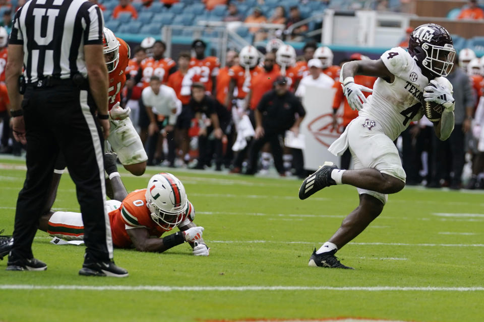 Texas A&M running back Amari Daniels (4) gets past Miami cornerback Te'Cory Couch (0) to score a touchdown during the first half of an NCAA college football game, Saturday, Sept. 9, 2023, in Miami Gardens, Fla. (AP Photo/Lynne Sladky)