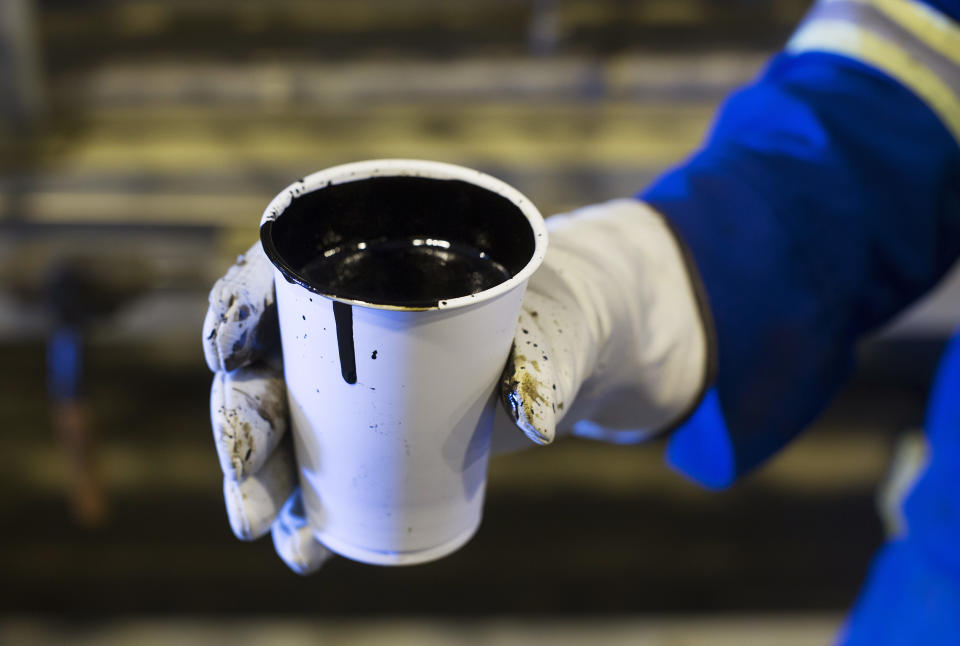 A worker holds a cup of heavy oil before it is shipped to the market at the Cenovus Energy Christina Lake Steam-Assisted Gravity Drainage (SAGD) project 120 km (74 miles) south of Fort McMurray, Alberta, August 15, 2013. Cenovus currently produces 100,000 barrels of heavy oil per day at their Christina Lake tar sands project. REUTERS/Todd Korol  (CANADA - Tags: ENERGY BUSINESS)