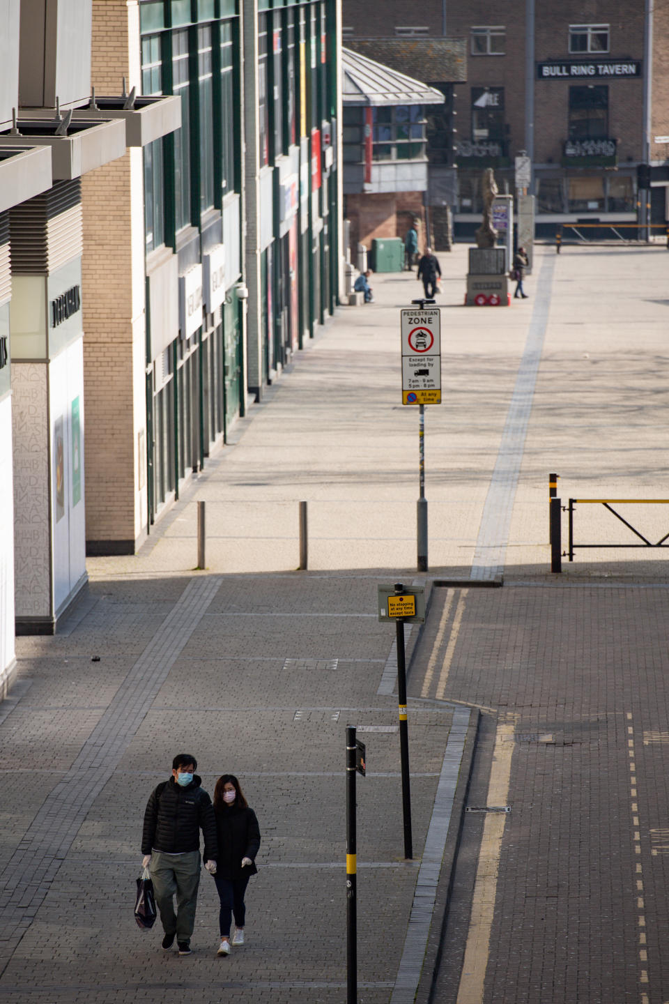 A couple wearing protevtive equipment walk by the Bullring in Birmingham, the day after Prime Minister Boris Johnson put the UK in lockdown to help curb the spread of the coronavirus.