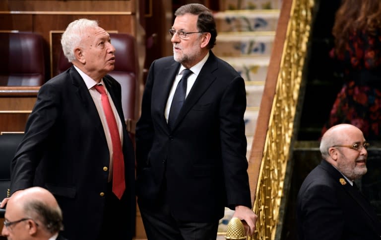 Spanish interim Prime Minister Mariano Rajoy (C) speaks with Spanish Minister of Foreign Affairs and Cooperation Jose Garcia-Margallo (L) during the parliamentary investiture vote for a prime minister, at the Spanish Congress