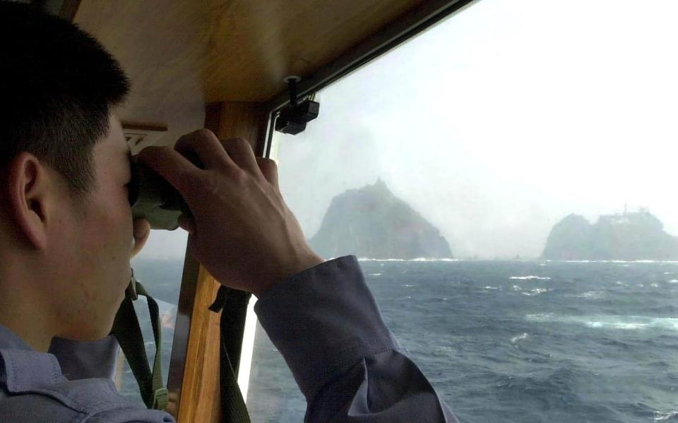 A South Korean coast guard looks at Dokdo islets, known as 