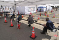 People wait in line to be screened for a high temperature before being vaccinated at the St. John's Well Child and Family Center just-opened COVID-19 vaccination site at the East Los Angeles Civic Center in Los Angeles, Thursday, March 4, 2021. California will begin sending 40% of all vaccine doses to the most vulnerable neighborhoods in the state to try to inoculate people most at risk from the coronavirus and get the state’s economy open more quickly, Gov. Gavin Newsom said Thursday in the latest shake-up to the state’s rules. (AP Photo/Damian Dovarganes)