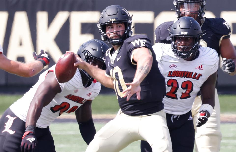 Oct 2, 2021; Winston-Salem, North Carolina, USA;  Wake Forest Demon Deacons quarterback Sam Hartman (10) throws a pass as Louisville Cardinals linebacker Jack Fagot (38) and linebacker Yasir Abdullah (22) put on the pressure during the second  quarter at Truist Field. Mandatory Credit: Reinhold Matay-USA TODAY Sports