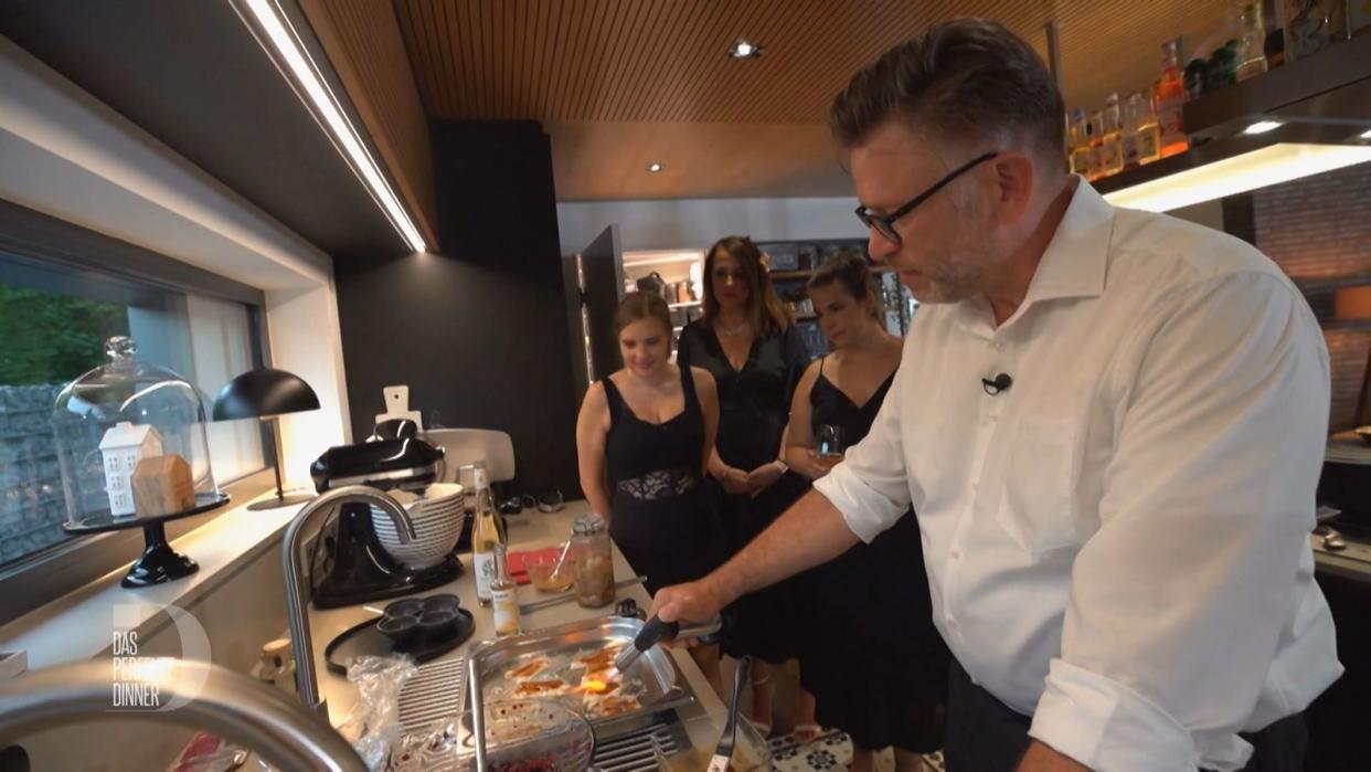 Show-Cooking zum Finale: Chris flämmt seine Forelle mit dem Bunsenbrenner. Tabea, Magda und Carmen schauen gespannt zu.
 (Bild: RTL)