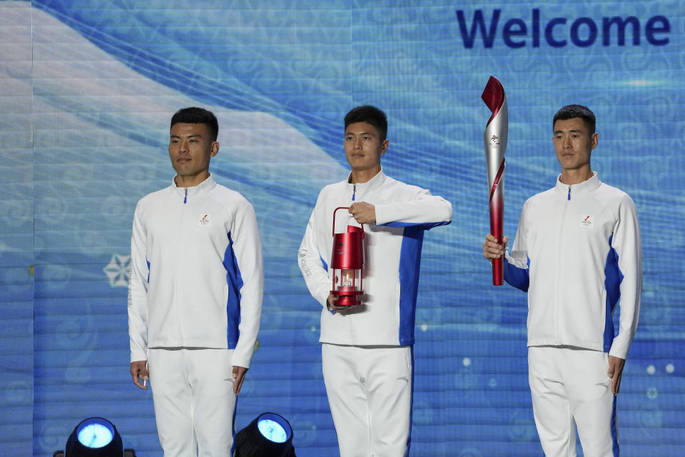 Volunteers hold the Olympic torch and the frame on stage during a welcome ceremony for the Frame of Olympic Winter Games Beijing 2022, held at the Olympic Tower in Beijing, Wednesday, Oct. 20, 2021. A welcome ceremony for the Olympic flame was held in Beijing on Wednesday morning after it arrived at the Chinese capital from Greece. While the flame will be put on display over the next few months, organizers said a three-day torch relay is scheduled starting February 2nd with around 1200 torchbearers in Beijing, Yanqing and Zhangjiakou. (AP Photo/Andy Wong)