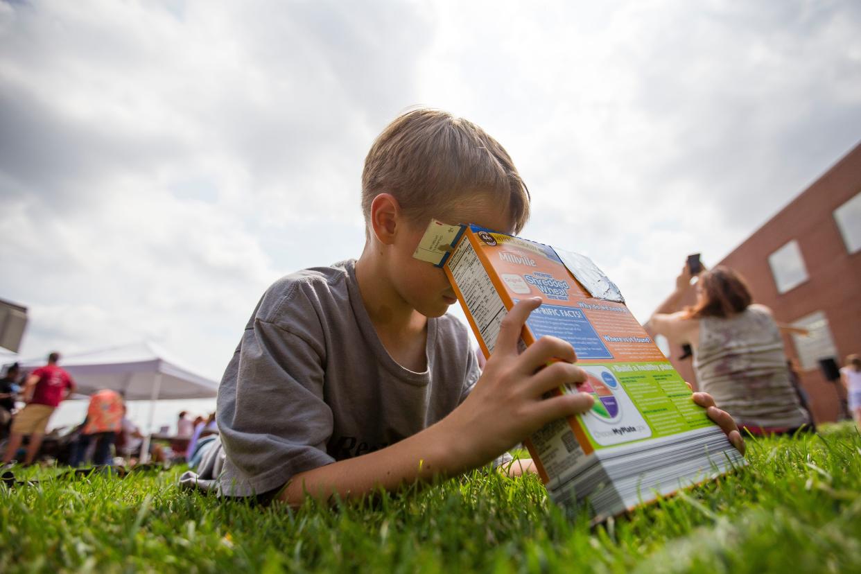 Ted Clingenpeel uses a box with a pinhole to view the sun during the solar eclipse watch party at the downtown branch of the St. Joseph County Public Library in South Bend on Monday, Aug. 21, 2017.