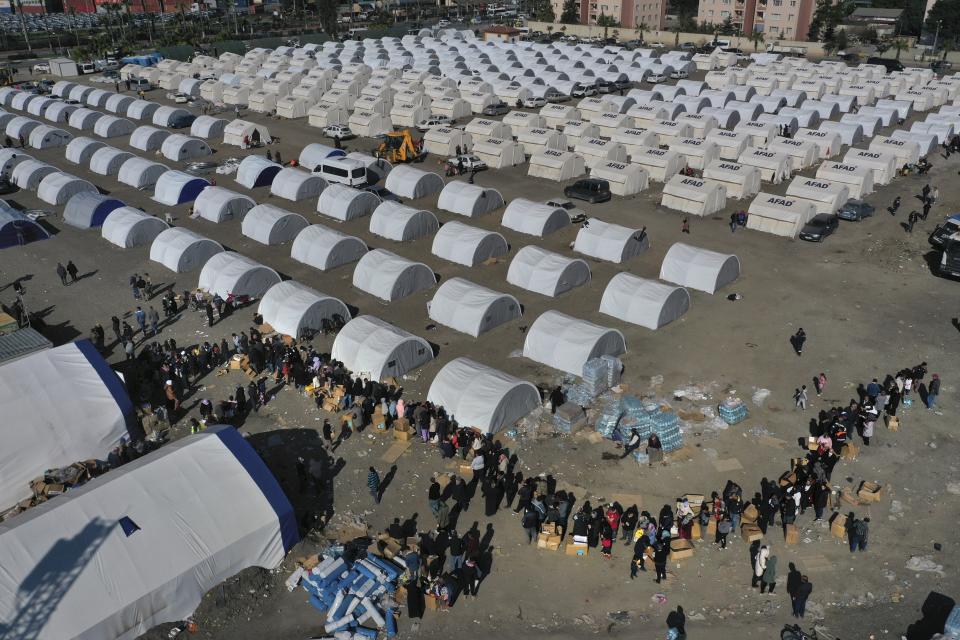 FILE - People who lost their houses in the devastating earthquake, lineup to receive aid supplies at a makeshift camp, in Iskenderun city, southern Turkey, on Feb. 14, 2023. Hundreds of thousands of people are seeking shelter after the Feb. 6 earthquake in southern Turkey left homes unlivable. Many survivors have been unable to find tents or containers dispatched to the region by the government and aid agencies, Instead they have sought refuge in any structure that can protect them from the winter conditions, including greenhouses, rail carriages and factories. (AP Photo/Hussein Malla)