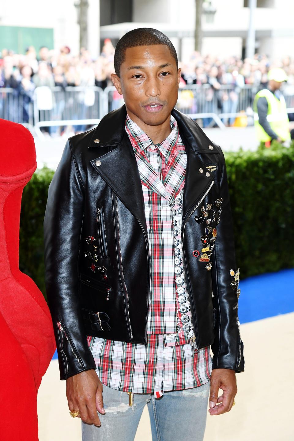 pharell williams attends the met gala in 2017 wearing a leather jacket, plaid shirt, and ripped jeans