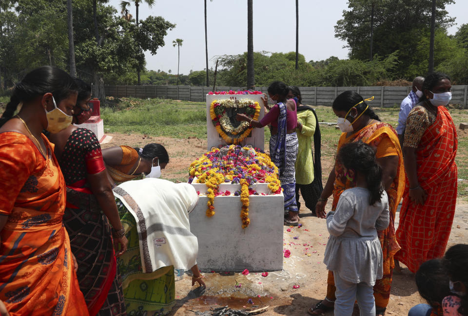 Relatives perform rituals at the grave of a person who died of COVID-19, at a crematorium on the outskirts of Hyderabad, India, Sunday, May 23, 2021. (AP Photo/Mahesh Kumar A.)