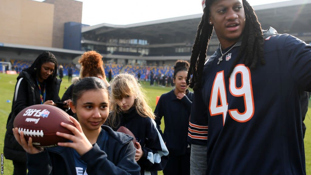 Chicago Bears player Tremaine Edwards showing a young girl how to throw a football at an NFL Flag event in London