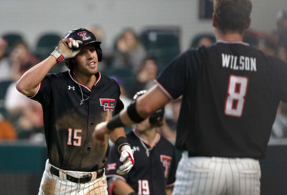 Texas Tech third baseman Parker Kelly (15) and shortstop Kurt Wilson (8) celebrate after Kelly scored in the second inning of the Red Raiders'  5-3 victory Wednesday against Kansas State.