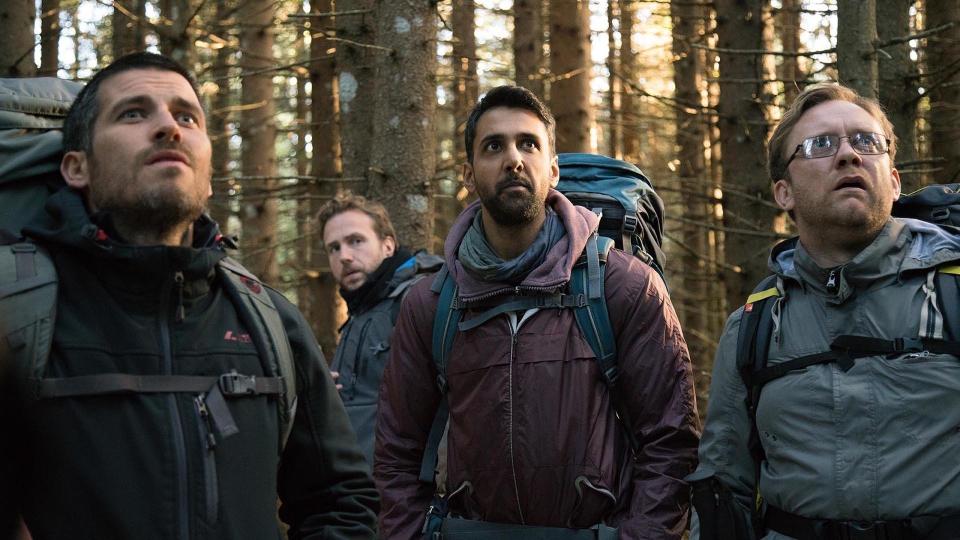 A still from the ritual shows four men looking scared in the woods