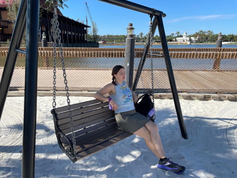 cat sitting on a swinging bench outside of the polynesian resort at disney world