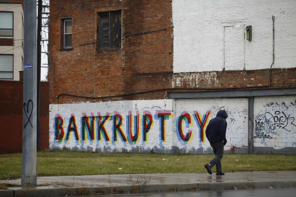 A man walk past graffiti in Detroit, Michigan, December 3, 2013. Detroit is eligible for the biggest municipal bankruptcy in U.S. history because the city is broke and negotiations with its thousands of creditors were unfeasible, a federal judge said on Tuesday in a wide-ranging ruling that also said the city could cut retiree pensions. REUTERS/Joshua Lott (UNITED STATES - Tags: CITYSCAPE BUSINESS)