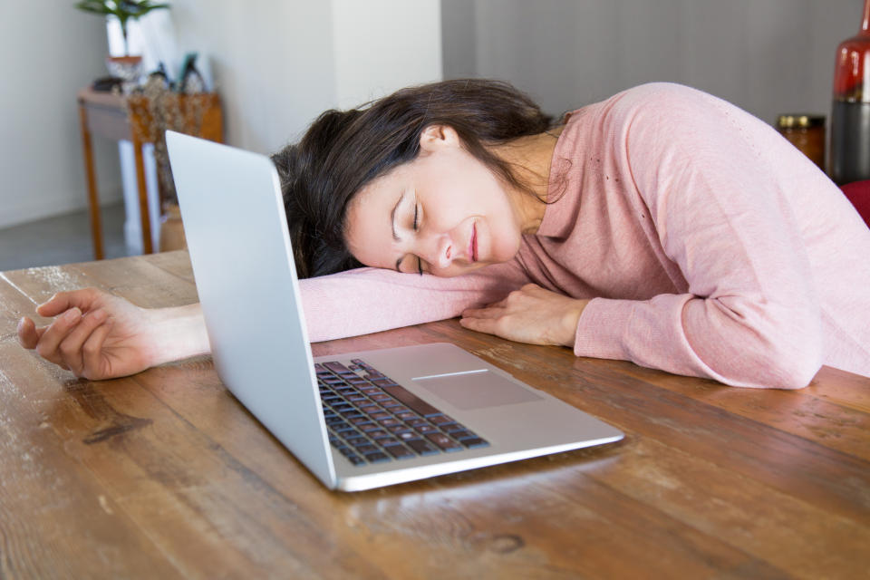 A woman sleeping in front of a laptop. (Source: Getty)