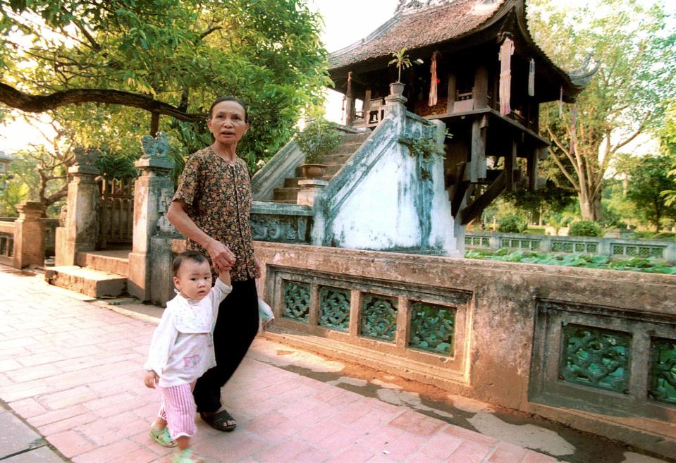 FILE - This May 24, 2000 file photo shows a woman and child walking past the One Pillar Pagoda in central Hanoi. Hanoi is packed with beautiful Buddhist temples, many of them ancient. Just follow the scent of burning incense and step away from the chaotic streets to take a moment to reflect and soak in the calm. The One Pillar Pagoda is among the city's most famous sites, but many Vietnamese flock to the Tay Ho Pagoda overlooking the city's large West Lake to leave offerings and pray, especially on auspicious days. (AP Photo/Doan Bao Chau)