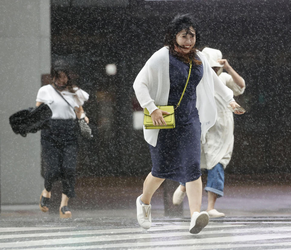 People make their way through the strong wind and rain in Kagoshima, southern Japan, Sunday, Sept. 18, 2022, as a powerful typhoon pounded southern Japan. (Kyodo News via AP)