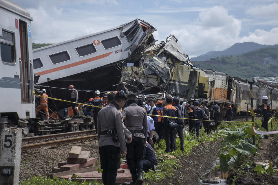 Rescuers inspect the wreckage after the collision between two trains in Cicalengka, West Java, Indonesia, Friday, Jan. 5, 2024. The trains collided on Indonesia's main island of Java on Friday, causing several carriages to buckle and overturn and killing at least a few people, officials said. (AP Photo/Abdan Syakura)