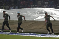Groundsmen run to cover the ground as rain interrupts the Indian Premier League cricket match between Punjab Kings and Royal Challengers Bengaluru in Dharamshala, India, Thursday, May 9, 2024. (AP Photo /Ashwini Bhatia)
