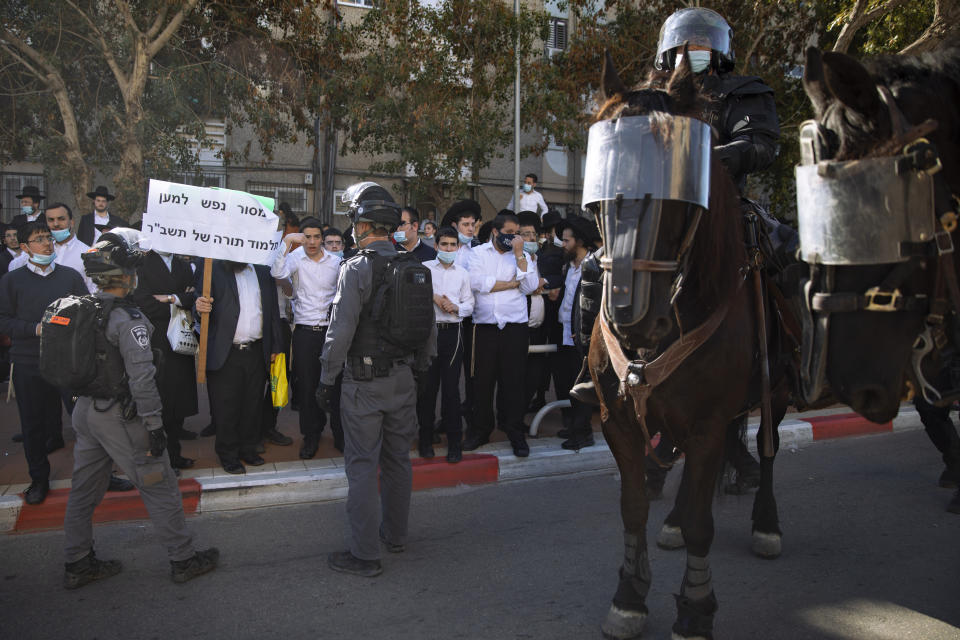 Israeli police officers clash with ultra-Orthodox Jews during a protest over the coronavirus lockdown restrictions, in Ashdod, Israel, Sunday, Jan. 24, 2021. As he seeks re-election, Prime Minister Benjamin Netanyahu has turned to a straightforward strategy: Count on the rock-solid support of his ultra-Orthodox political allies and stamp out the coronavirus pandemic with one of the world’s most aggressive vaccination campaigns. But with ultra-Orthodox communities openly flouting safety guidelines and violently clashing with police trying to enforce them, this marriage of convenience is turning into a burden. (AP Photo/Oded Balilty)