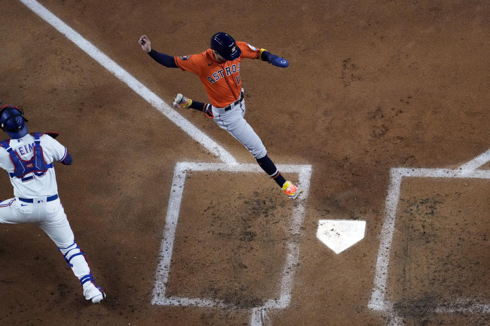 Houston Astros' Mauricio Dubon (14) scores as Texas Rangers catcher Jonah Heim covers home plate during the second inning in Game 3 of the baseball American League Championship Series Wednesday, Oct. 18, 2023, in Arlington, Texas. (AP Photo/Godofredo A. Vasquez)