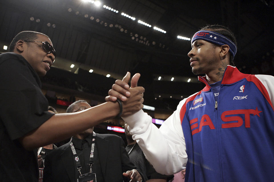 ARCHIVO - El rapero Jay-Z, a la izquierda, le da la mano a Allen Iverson, del NBA All-Star Philadelphia 76ers, antes del inicio del partido de baloncesto NBA All-Star en Houston, el 19 de febrero de 2006. Así como la banda sonora de una película ayuda a los espectadores a seguir la acción de la narración a través de cada giro de la trama, el hip hop ha hecho lo mismo con el basquetbol través de la NBA. (Foto AP/LM Otero, archivo)