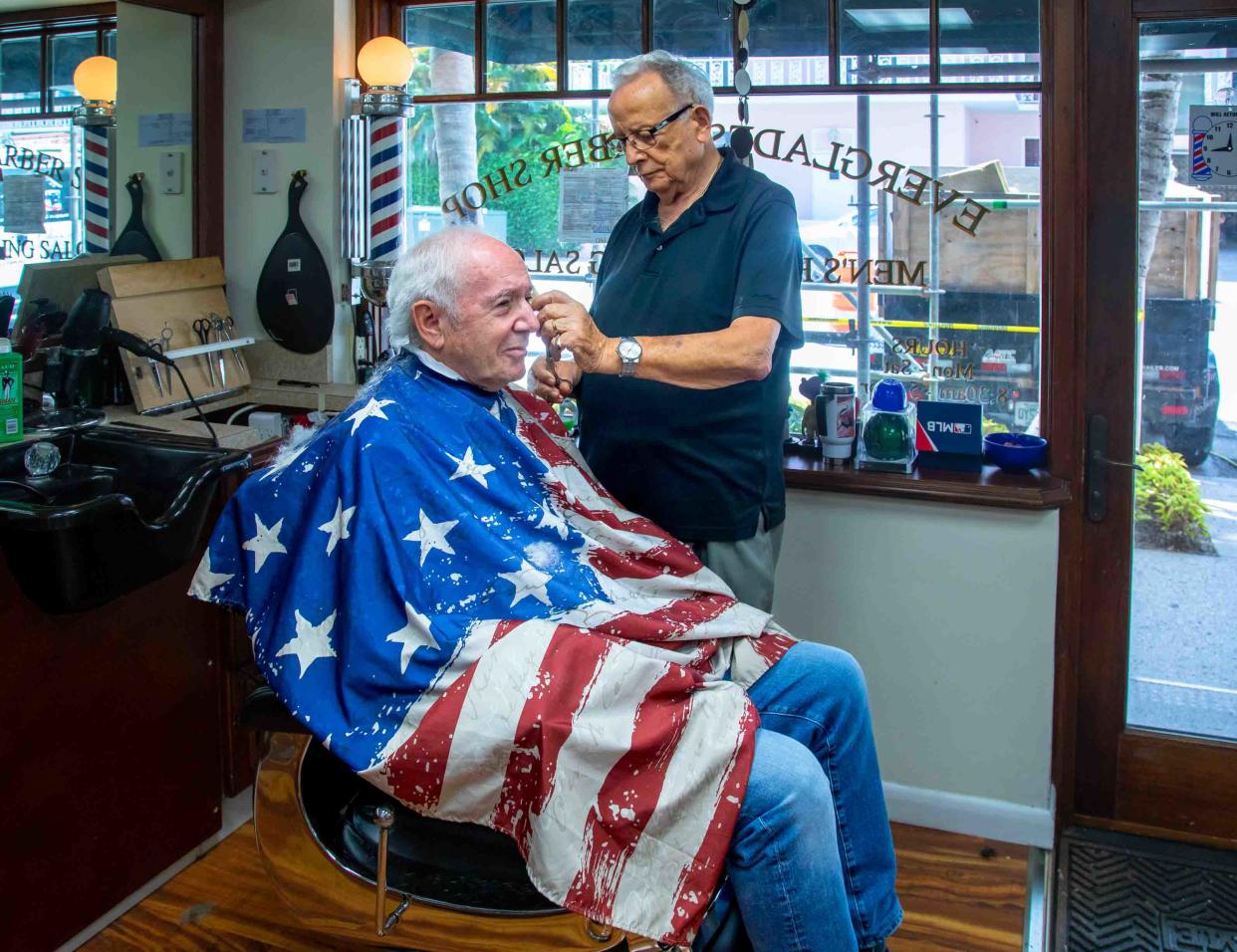 Leo Martino, 90, gives his client Leslie Evans a haircut on Aug. 29, his last day of work at the Everglades Barber Shop in Palm Beach.