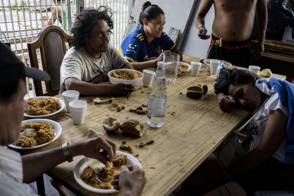 Personas almorzando en el comedor social de la Casa Comunitaria del Fondo en el barrio Padre Carlos Múgica de Buenos Aires, Argentina, el miércoles 13 de diciembre de 2023. El gobierno argentino eliminó subsidios al transporte y energía y devaluó el peso a más de la mitad, de 400 a 800 pesos por dólar, como parte de las medidas de ajuste que el nuevo presidente, Javier Milei, defiende ante las urgencias económicas del país. (AP Foto/Rodrigo Abd)