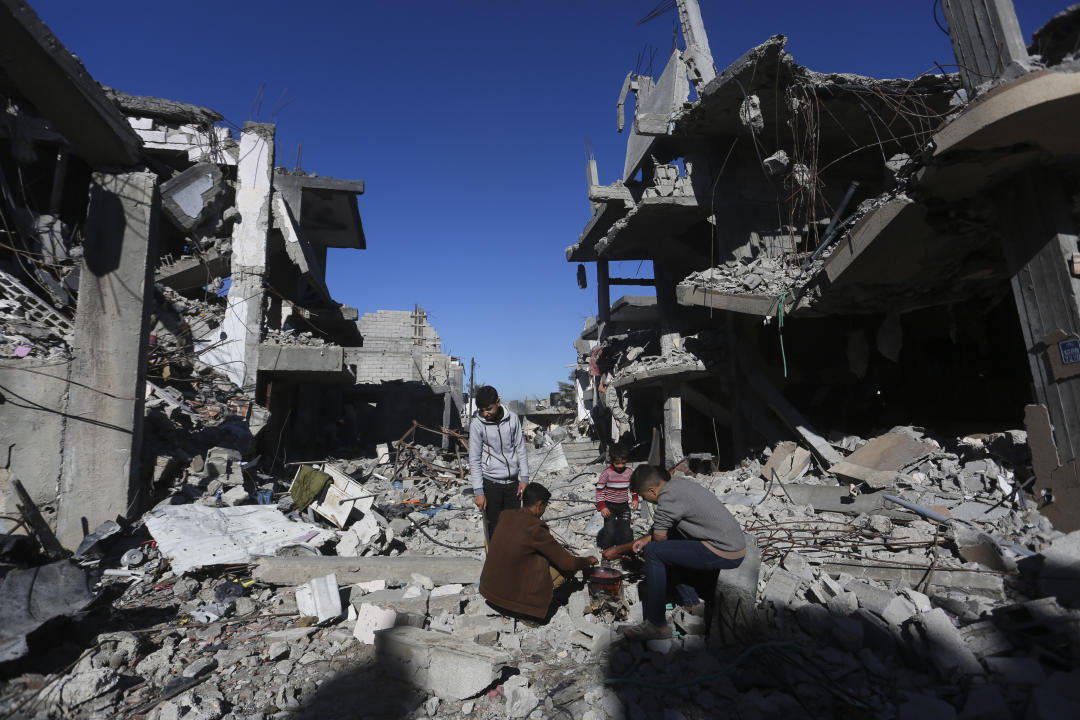 Palestinians cook bread by their destroyed homes in Kuza' a Gaza Strip during the temporary ceasefire