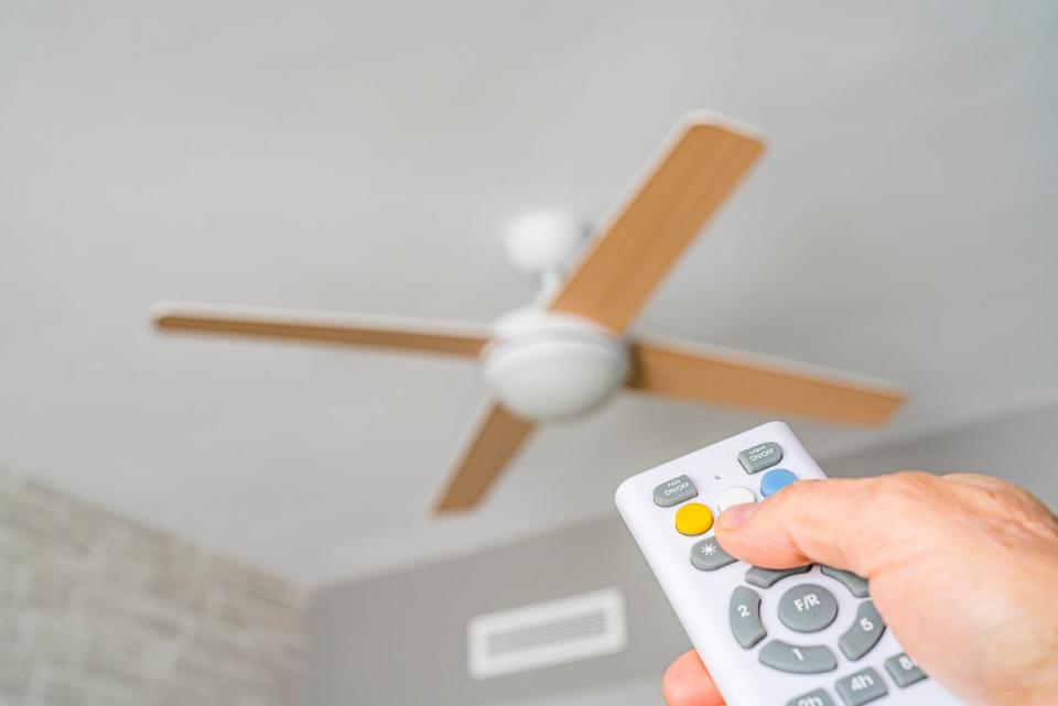 Close up of a hand holding a remote control aiming to ceiling fan. High resolution 42Mp indoors digital capture taken with SONY A7rII and Zeiss Batis 40mm F2.0 CF lens