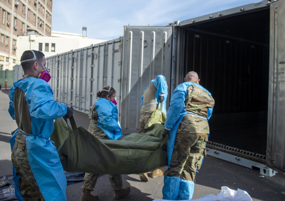 FILE - In this Jan. 12, 2021 photo provided by the Los Angeles County Department of Medical Examiner-Coroner, National Guard members assisting with processing COVID-19 deaths, placing them into temporary storage at the medical examiner-coroner's office in Los Angeles. The seven-day rolling average of daily deaths is rising in 30 states and the District of Columbia, and on Monday, Jan 18, 2021, the U.S. was approaching 398,000, according to data collected by Johns Hopkins University, by far the highest of any country in the world. (Los Angeles County Department of Medical Examiner-Coroner via AP, File)