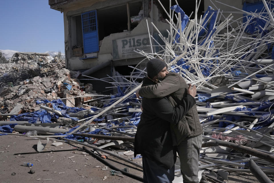 Syrian men comfort each other, in Kahramanmaras city, southern Turkey, Wednesday, Feb. 15, 2023. Thousands left homeless by a massive earthquake that struck Turkey and Syria a week ago packed into crowded tents or lined up in the streets for hot meals as the desperate search for survivors entered what was likely its last hours. (AP Photo/Hussein Malla)