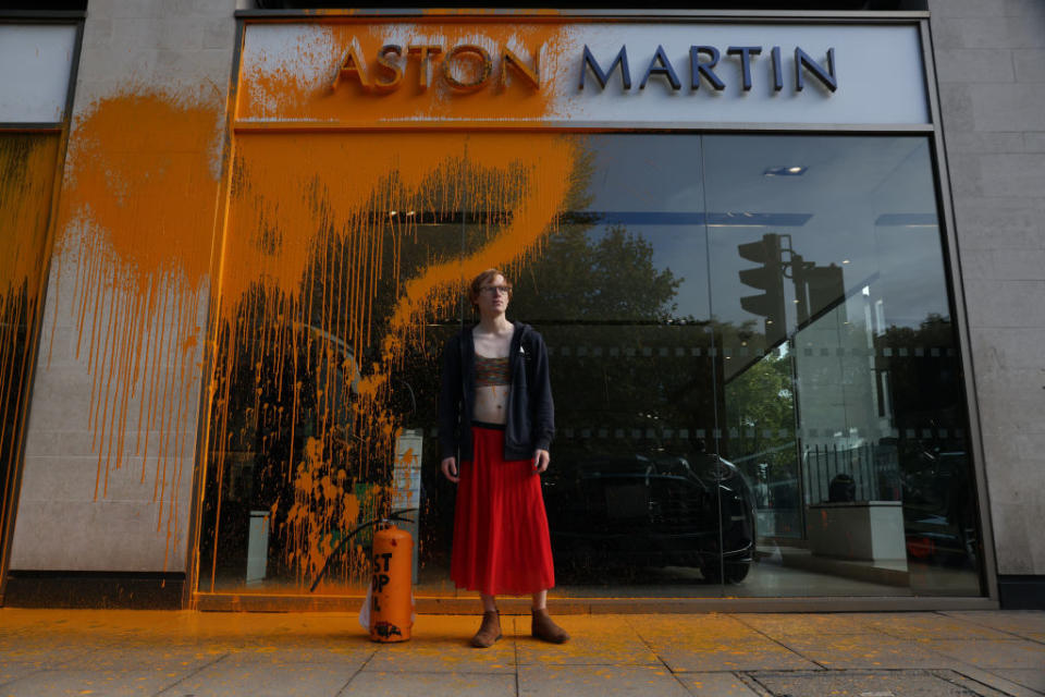 A Just Stop Oil demonstrator sprays an orange substance on an Aston Martin store in Mayfair on October 16, 2022 in London, England.<span class="copyright">Hollie Adams—Getty Images</span>