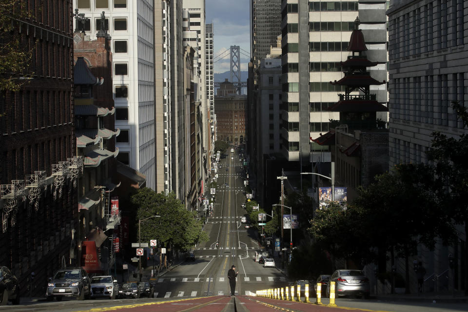 FILE - In this March 21, 2020, file photo, a man stands in the middle of a cable car tracks on a near empty California Street in San Francisco. On the morning of March 15, as Italy became the epicenter of the global coronavirus pandemic, a half dozen high-ranking California health officials held an emergency conference call to discuss a united effort to contain the spread of the virus in the San Francisco Bay Area. That call and the bold decisions that came in the hours afterward have helped California avoid the kind of devastation from the virus in parts of Europe and New York City. (AP Photo/Jeff Chiu, File)