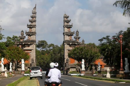 Motorists pass a damaged gate following an earthquake in Nusa Dua